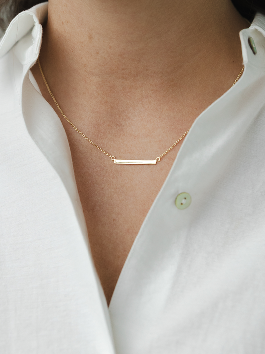 Gold necklace on a person wearing a white shirt