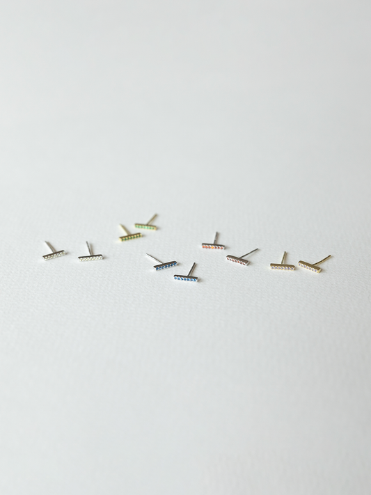 Small birthstone earrings laid out on a white background