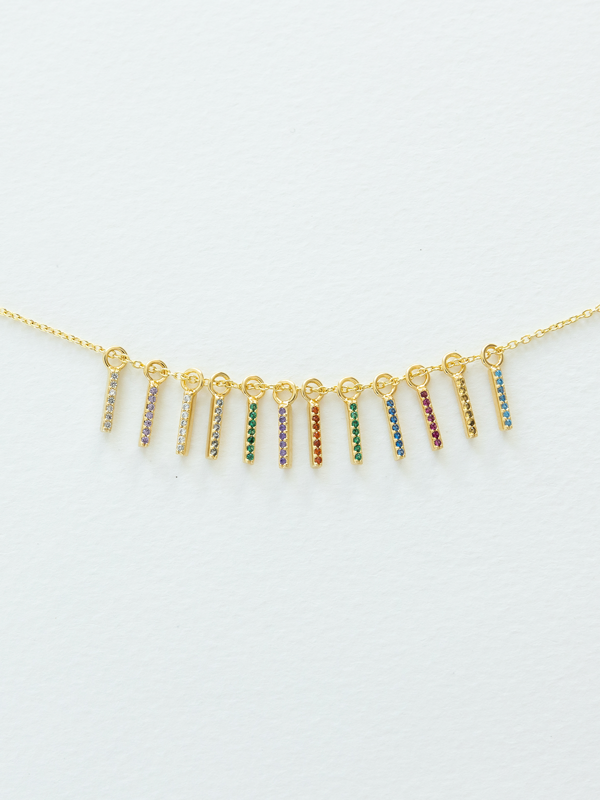 Gold necklace with birthstone pendants on a light gray background