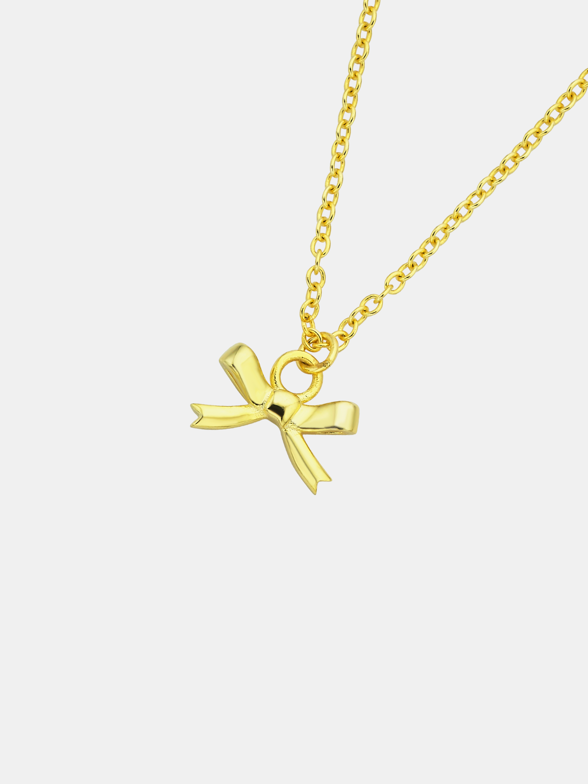 Gold necklace with a bow-shaped pendant on a light gray background