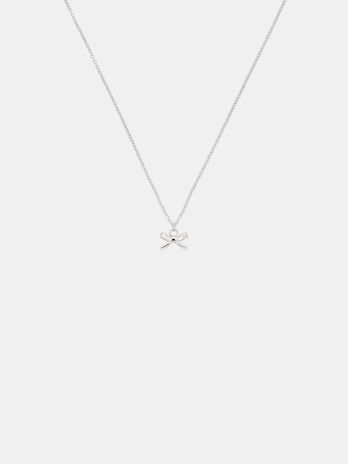 Silver necklace with a bow pendant on a white background