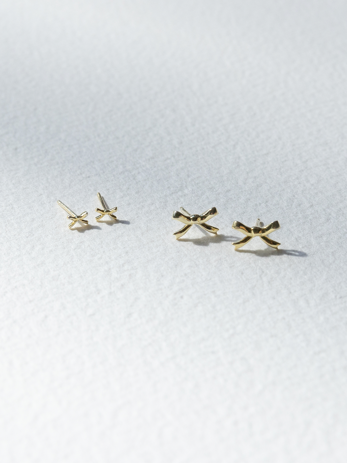Gold bow-shaped earrings on a white background