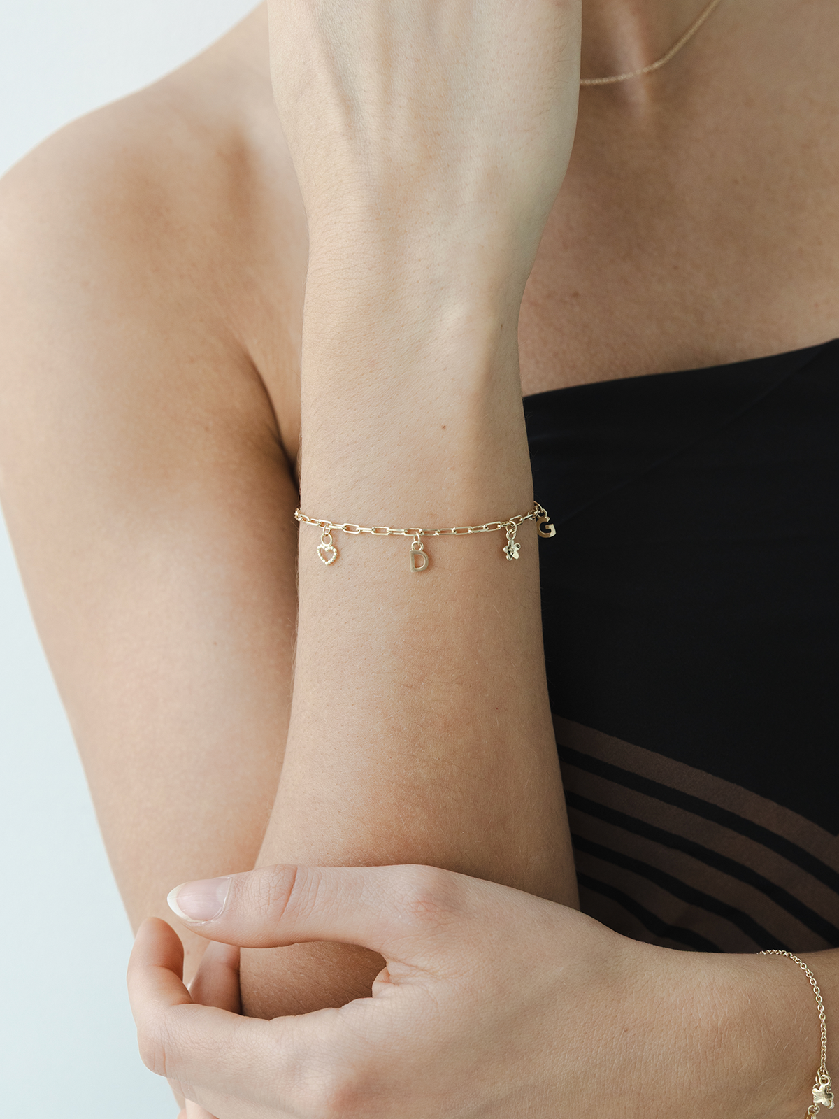 Solid gold choose your charms bracelet on a wrist against a neutral background