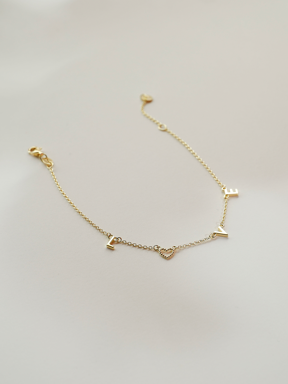 Gold bracelet with letter charms on a light gray background