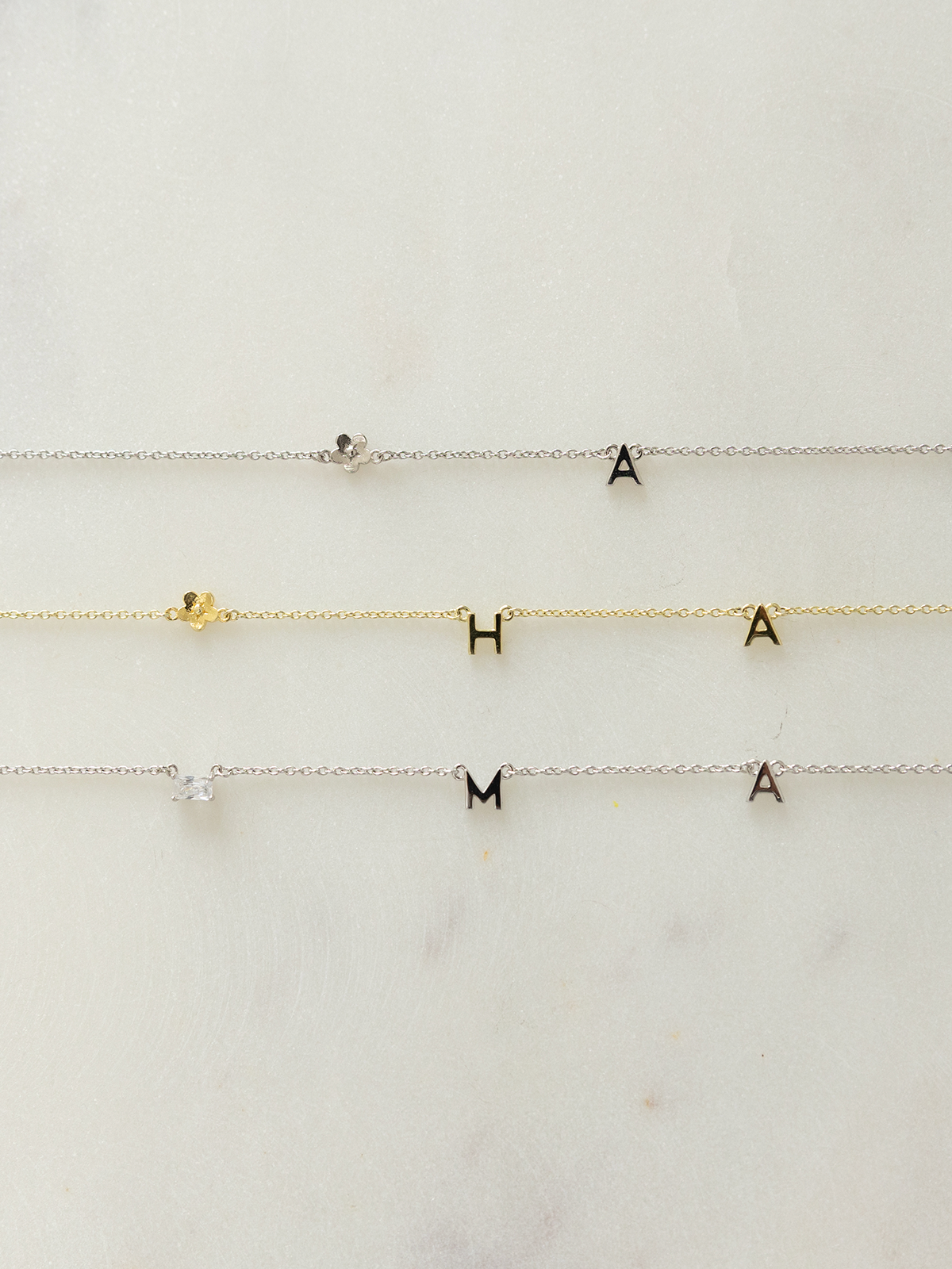 Three choose your letters jewellery in silver & gold with letter and pendant charms on a white background