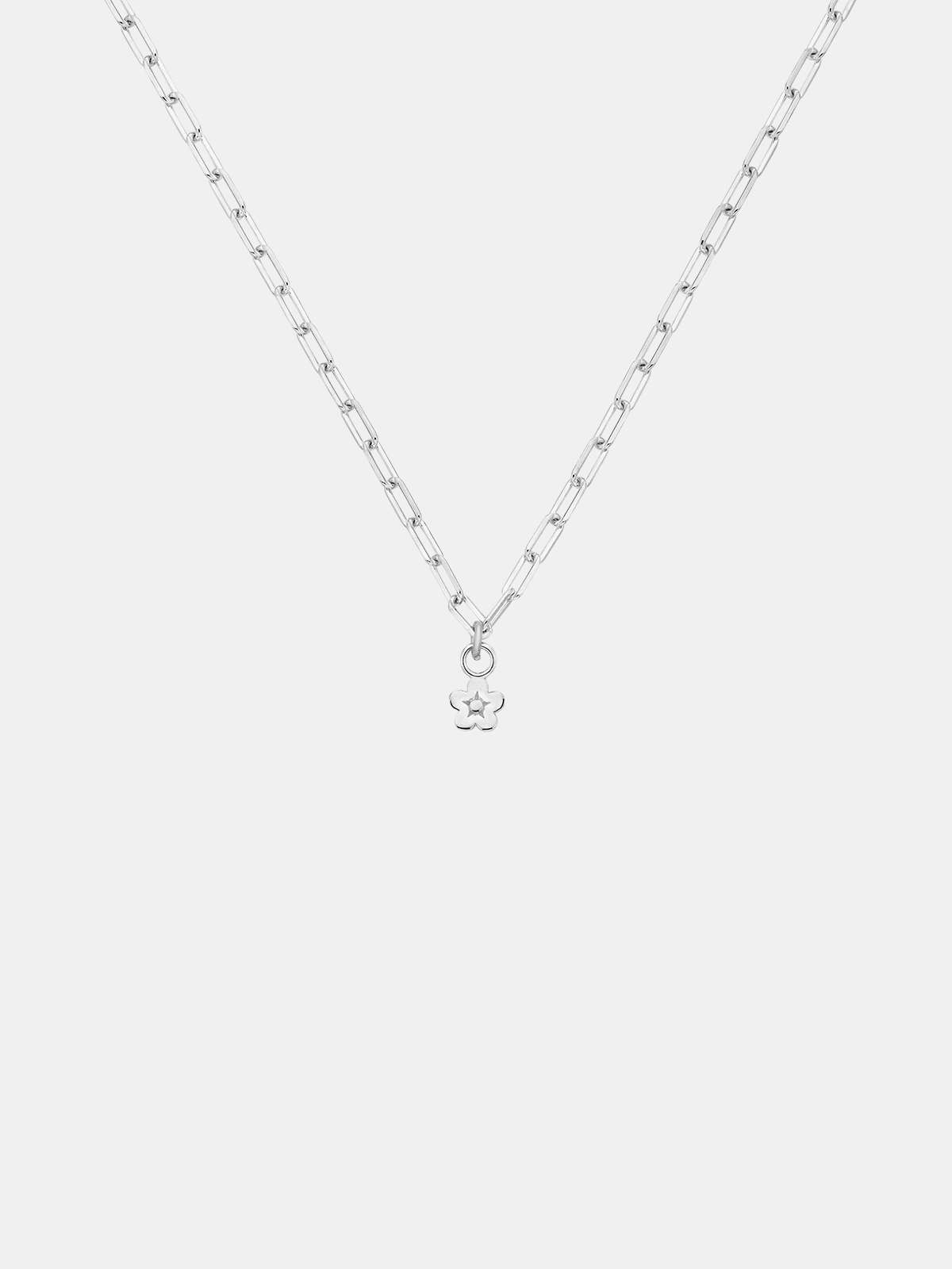 Gold necklace with a daisy day flower pendant on a light gray background