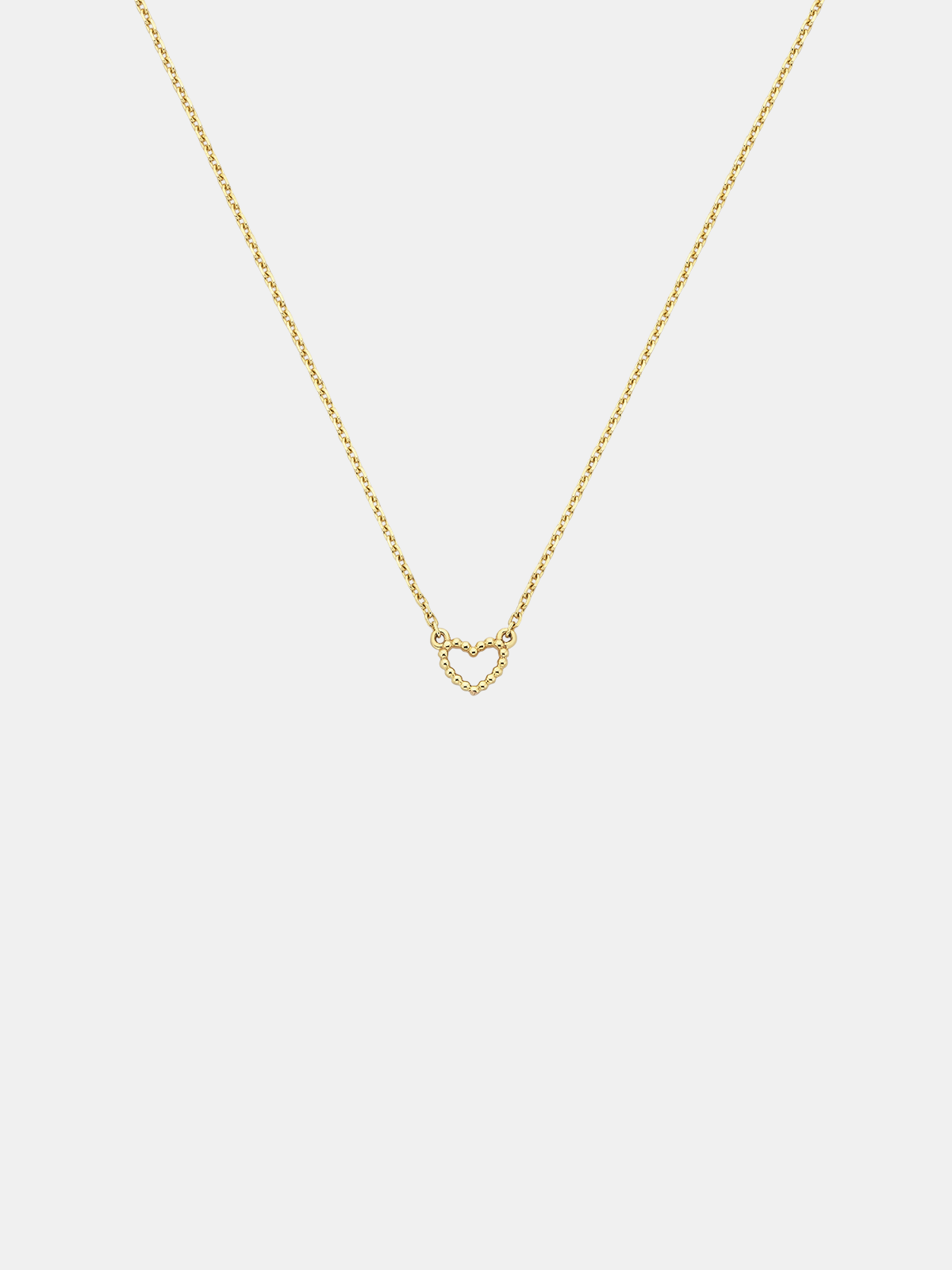 Solid gold dotty love heart-shaped pendant necklace on a light gray background