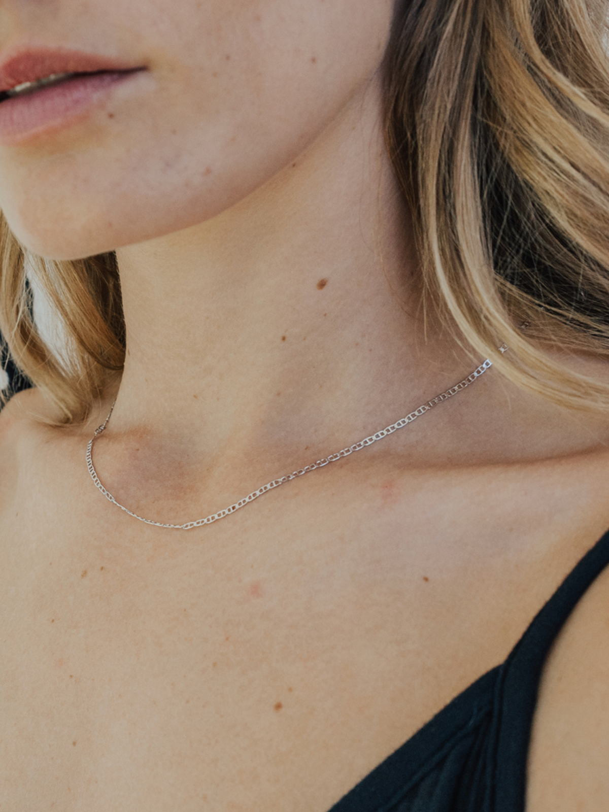 Close-up of a person wearing a delicate silver necklace.