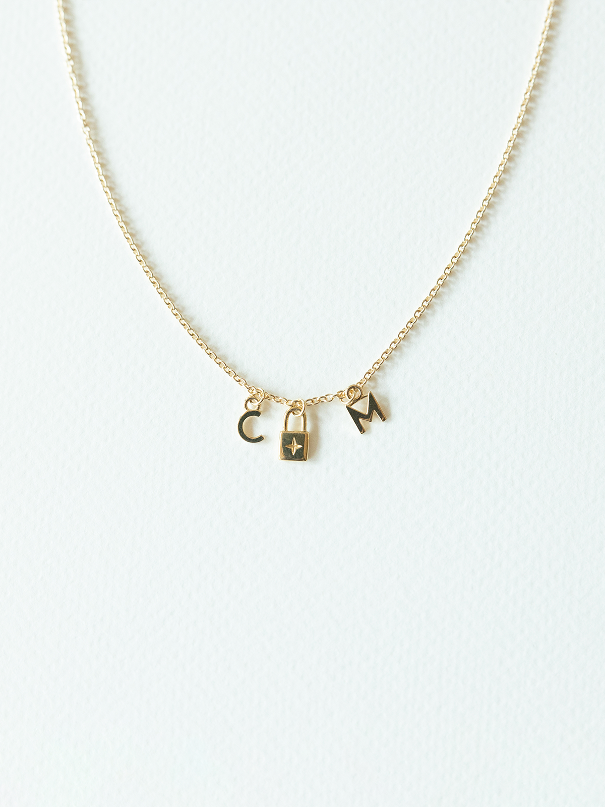 Solid gold mix it up necklace on cable chain with three small pendants on a white background