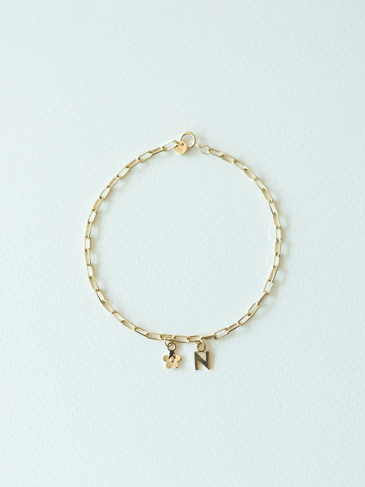Mix It Up solid gold charm bracelet on a mini links chain on a light blue background
