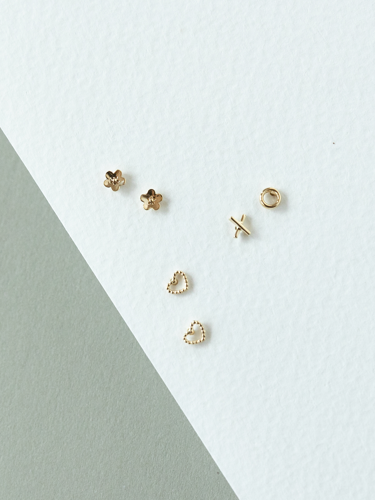 Set of micro solid gold earrings on a light grey background