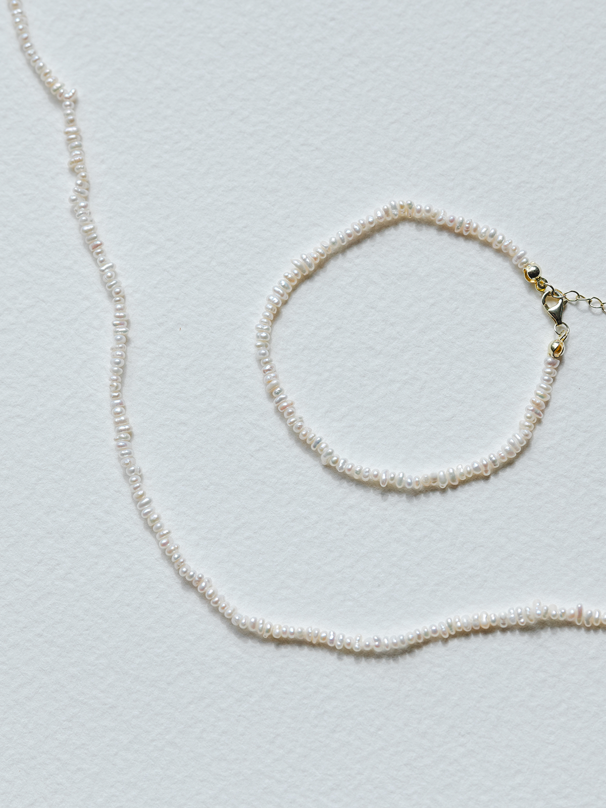 Pearl necklace and bracelet on a light gray background