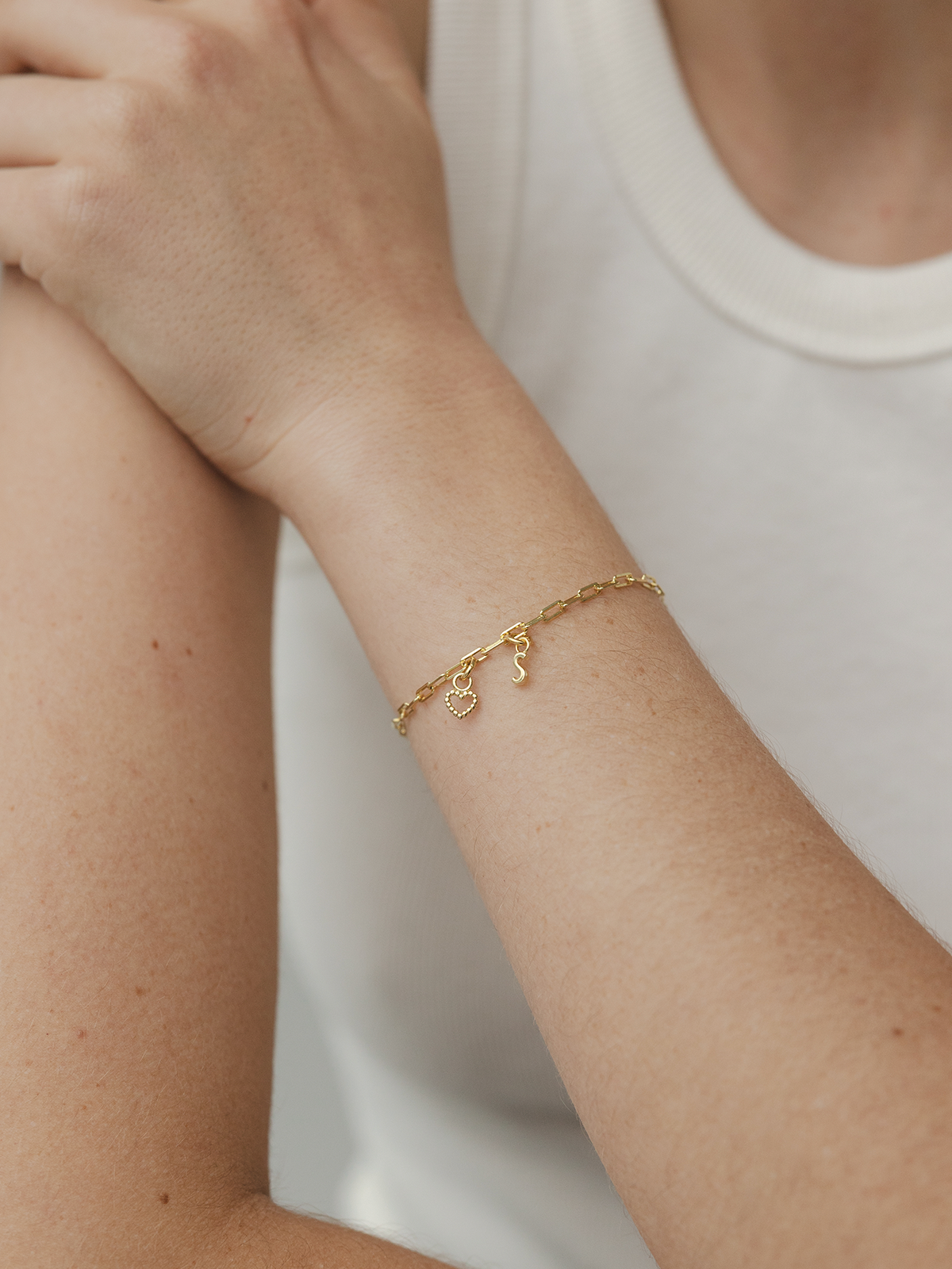 Gold bracelet on a person's wrist with a plain background