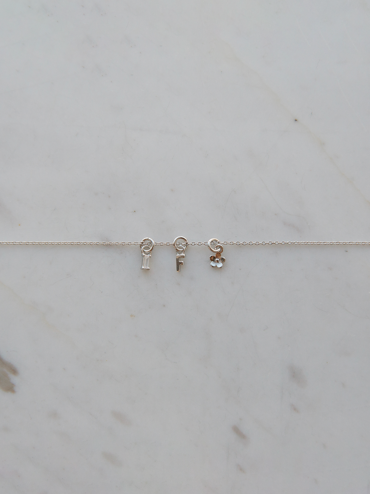 Silver mix it up bracelet with letter and other charms on a marble surface