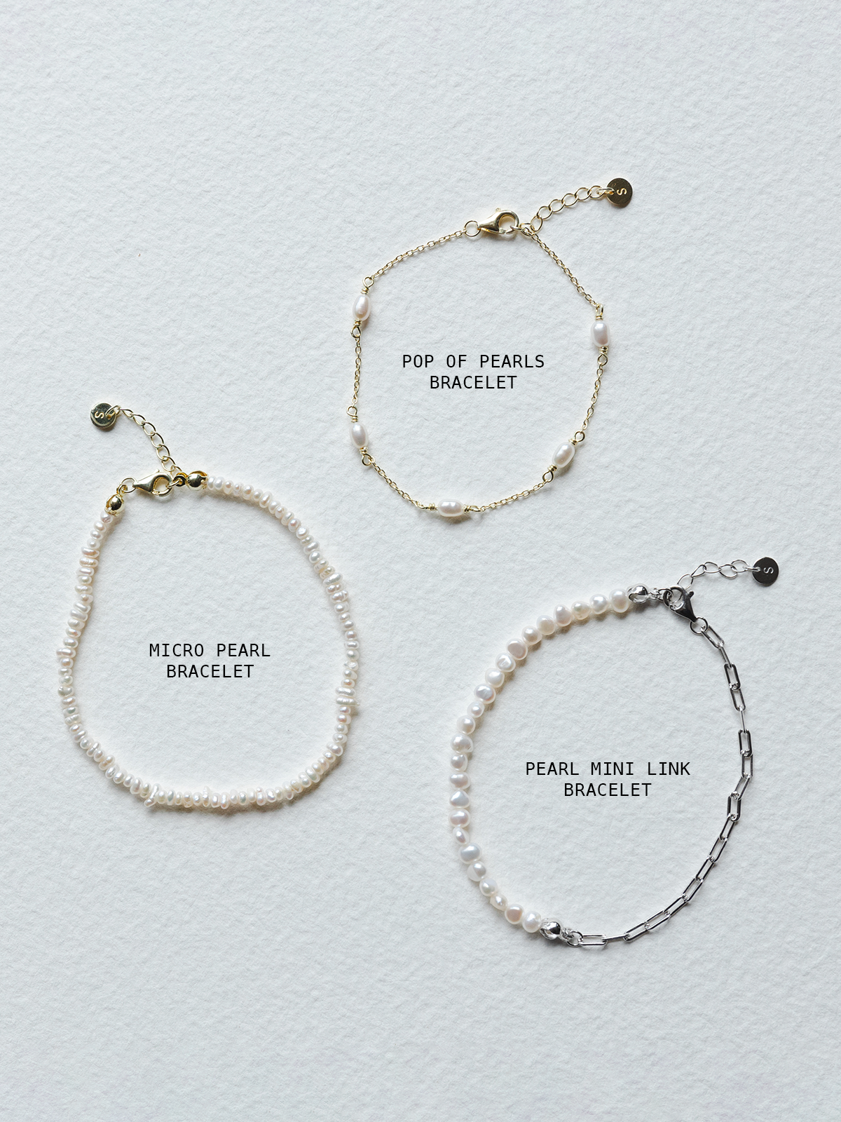 Three pearl bracelets with labels on a light gray background