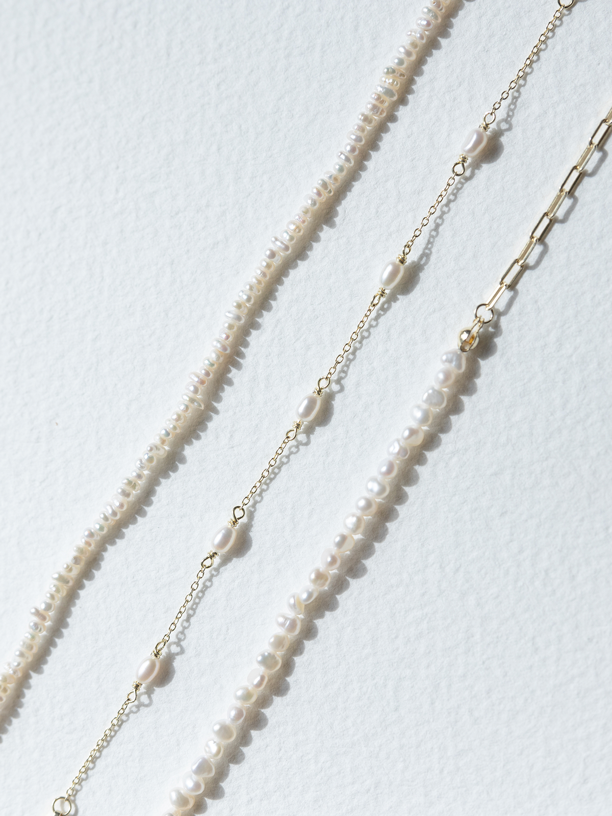 Three varying SOPHIE Store pearl bracelets on a white background