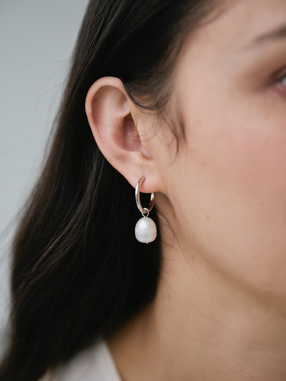 Pearl earring worn by a person with a neutral background
