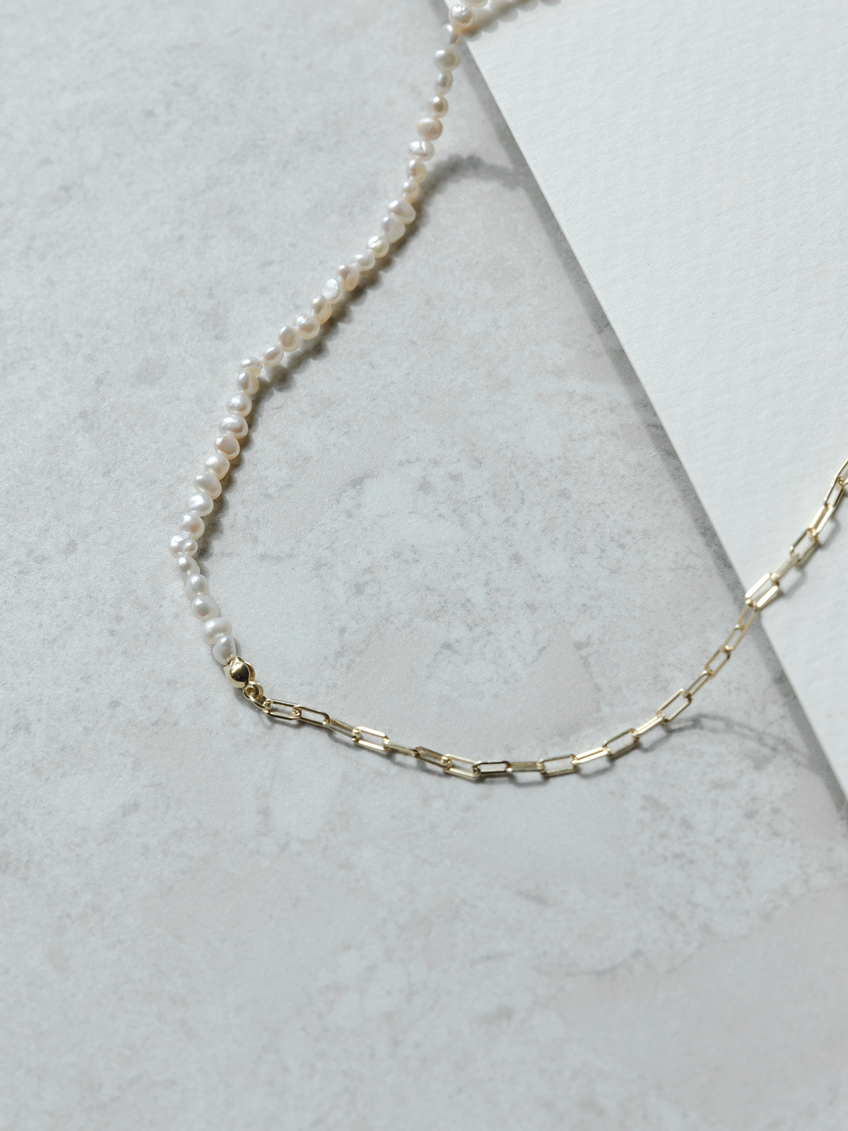 Necklace with pearl and gold chain on a light gray background