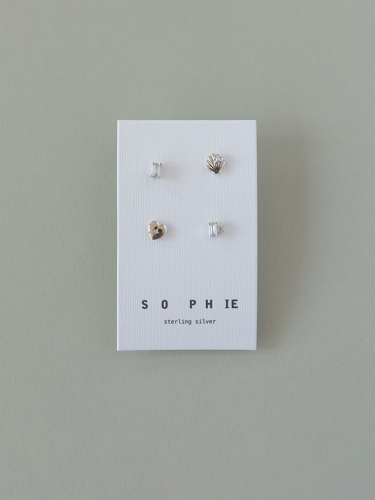 Set of four silver earrings on a 'Sophie' branded card against a gray background