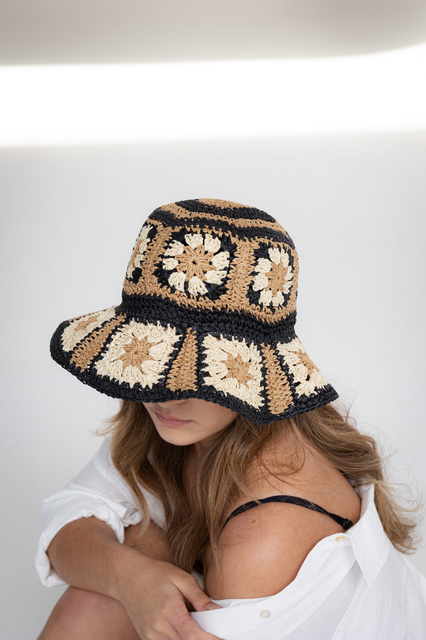 Woman wearing a crocheted sun hat with a geometric pattern on a white background