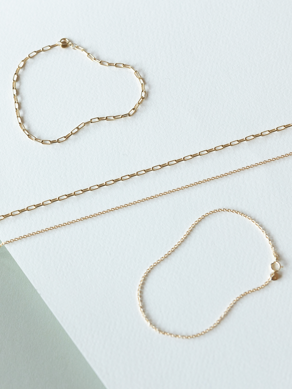 Solid gold necklaces & bracelets - mini links & cable chains on a light background