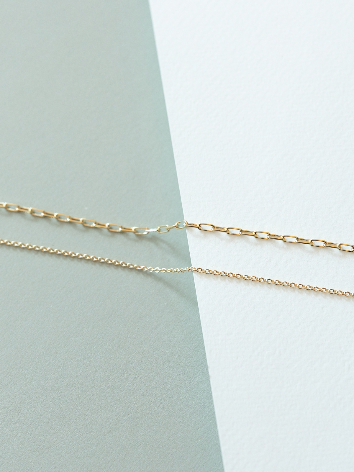 Mini links (top) and cable (bottom) chains on a light green and white background