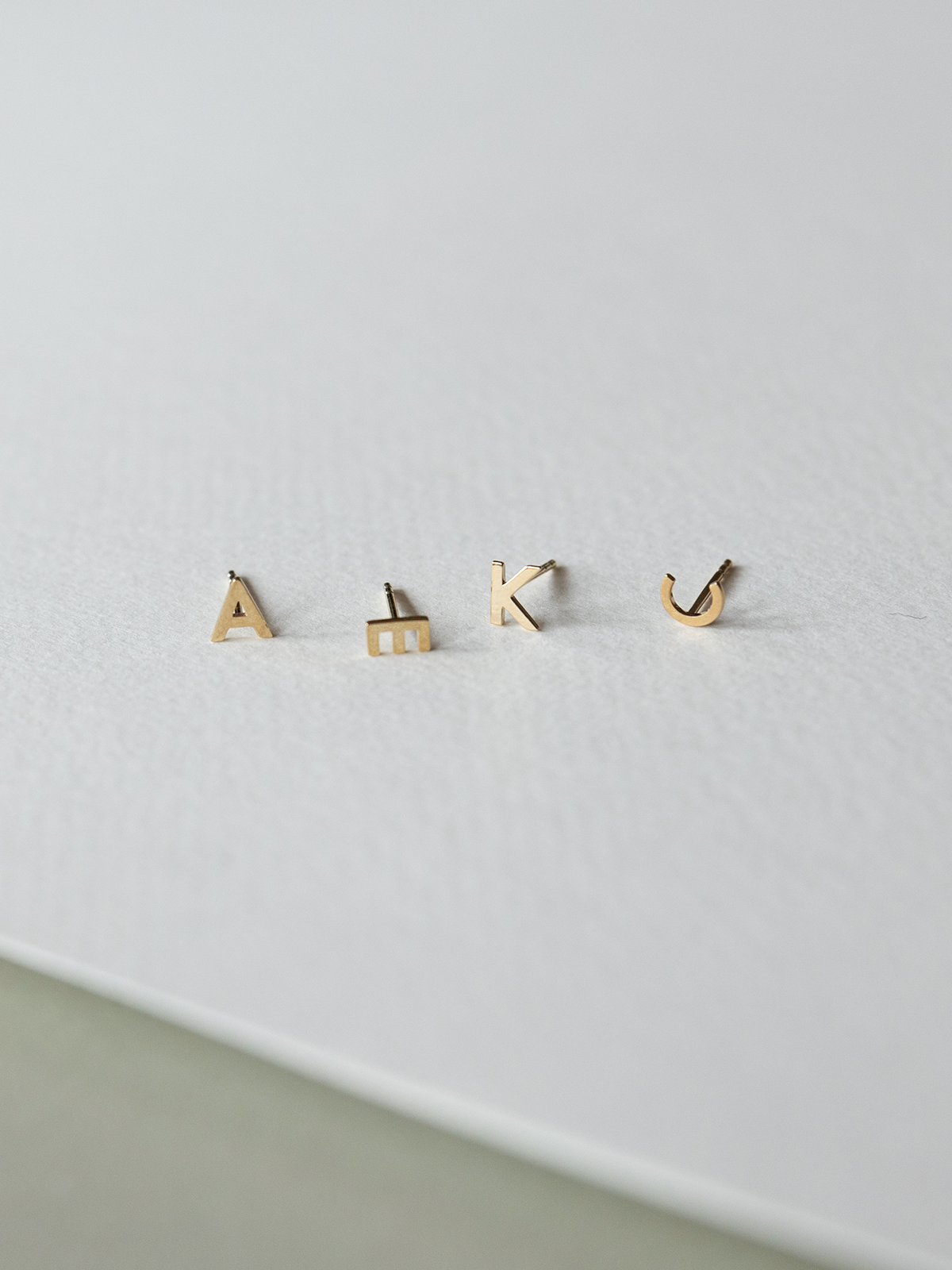 Set of solid gold letter earrings on a light gray background