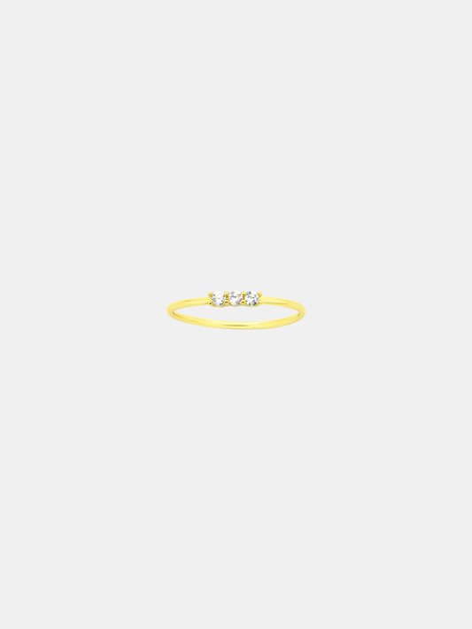 Gold ring with three stones on a light beige background