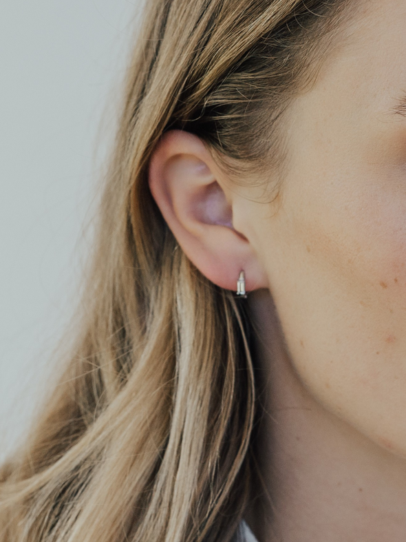 Close-up of a person wearing a small earring with a neutral background
