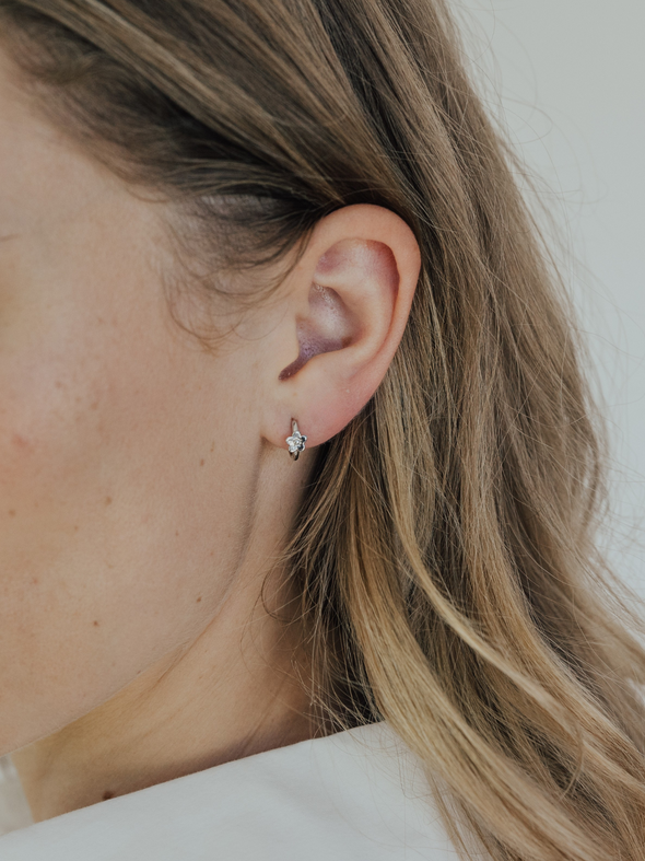 Close-up of a person wearing a heart-shaped earring with a blurred background