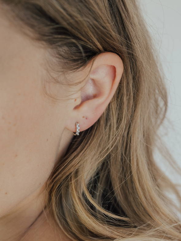 Close-up of an ear with a small earring against a neutral background