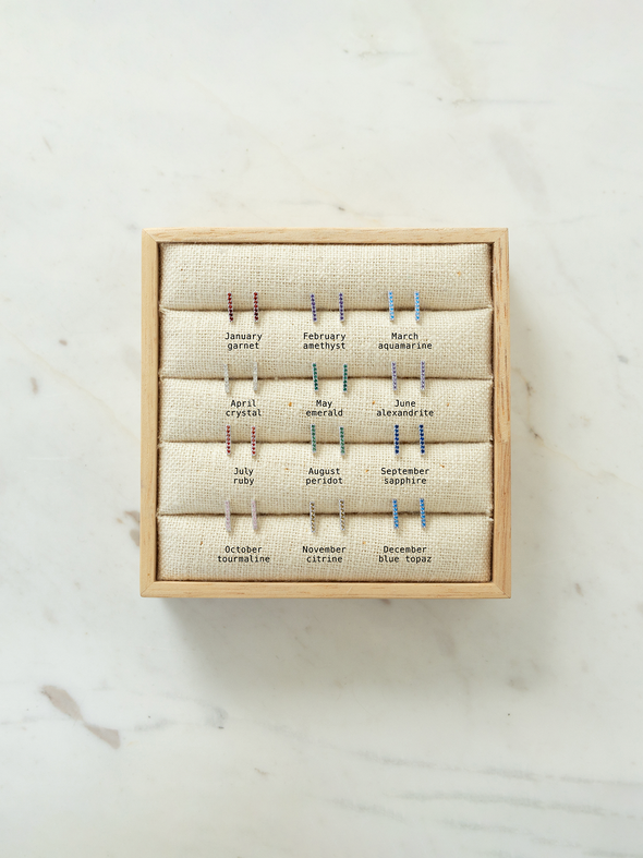Set of birthstone earrings in a wooden box on a marble surface. Shows what month is what CZ birthstone