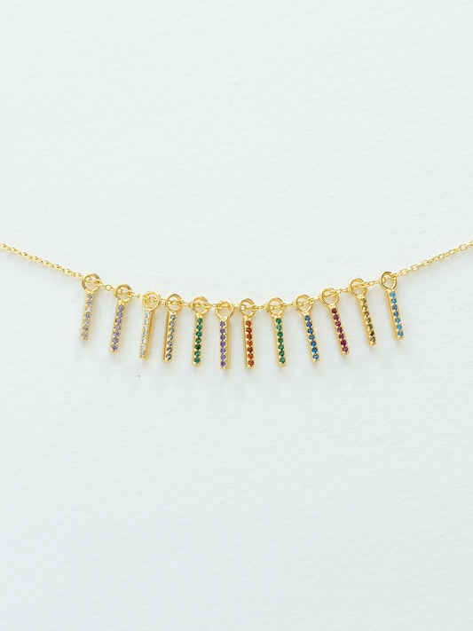 Gold necklace with birthstone pendants on a light gray background