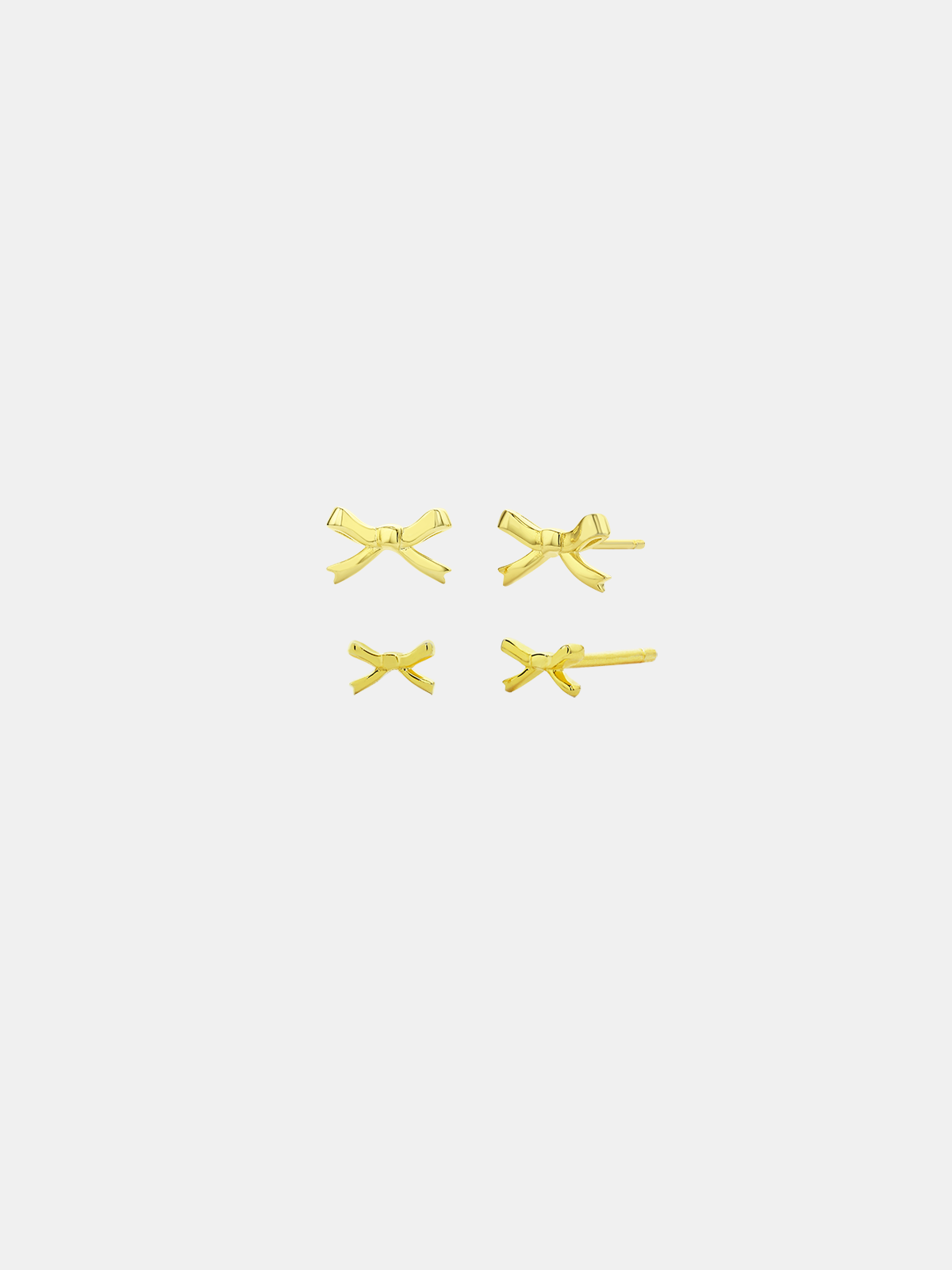 Set of gold bow-shaped earrings on a light grey background