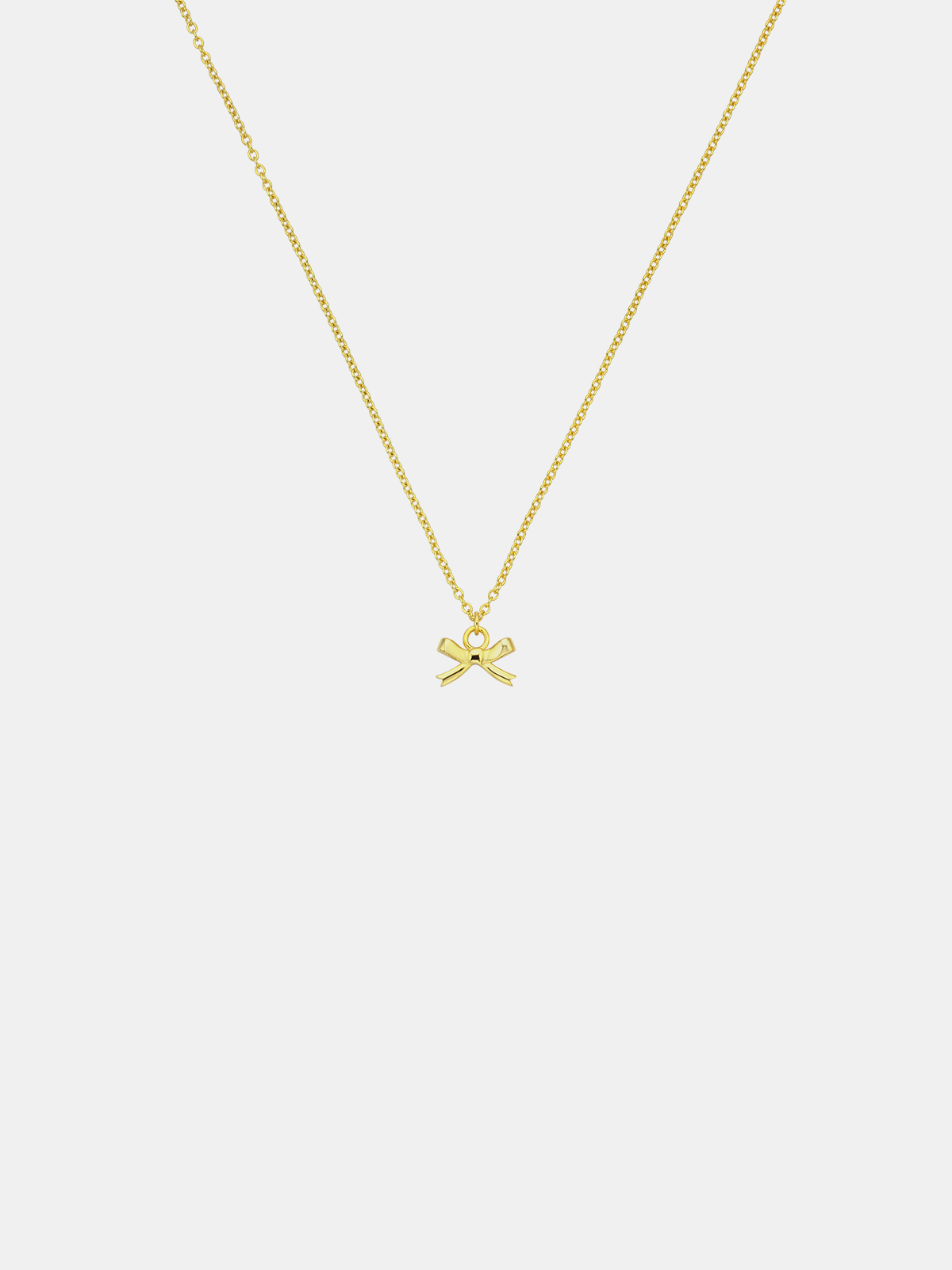 Gold necklace with a bow pendant on a light gray background