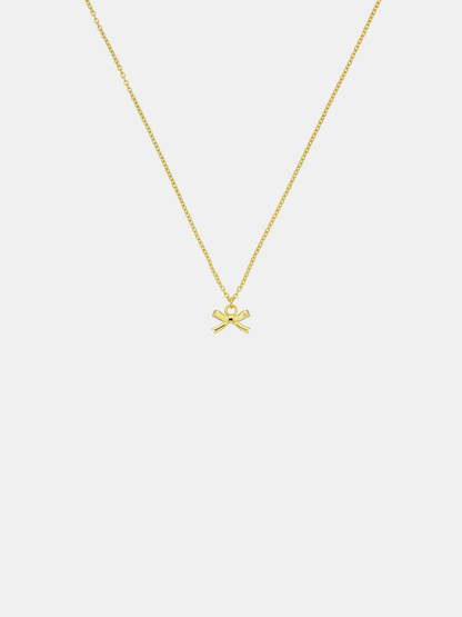 Gold necklace with a bow pendant on a light gray background