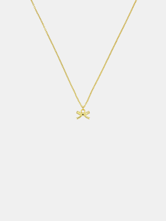 Gold necklace with a bow pendant on a light gray background