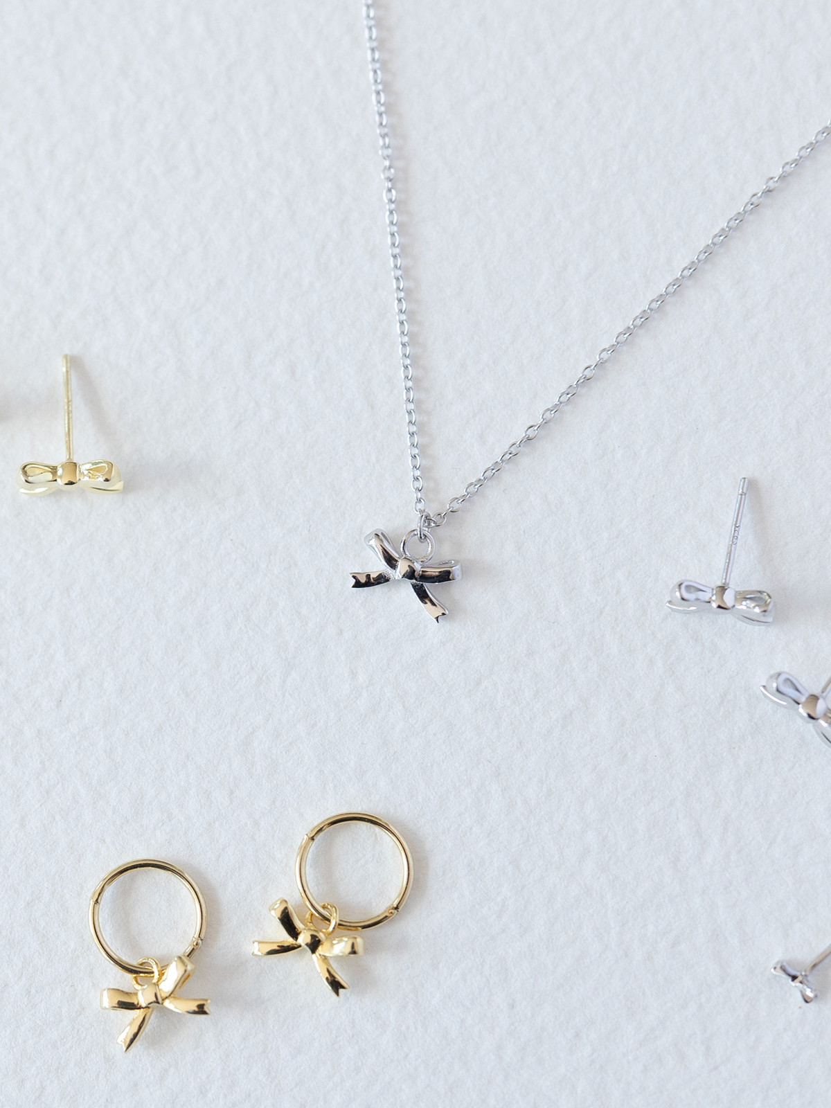 Gold and silver jewelry including rings, earrings, and a necklace on a white background