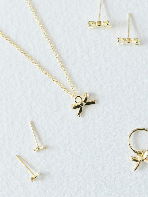 Gold jewelry set including necklace, earrings, and pendants on a white background