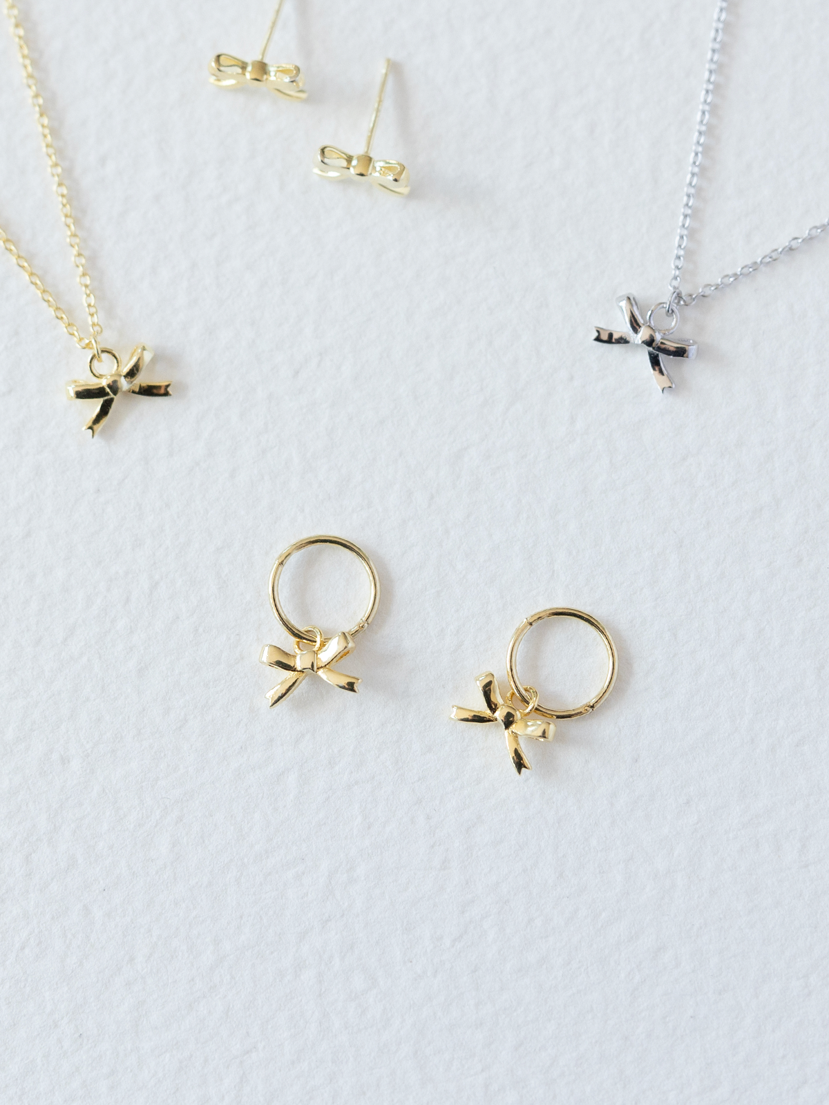 Gold and silver jewelry with bow designs on a white background