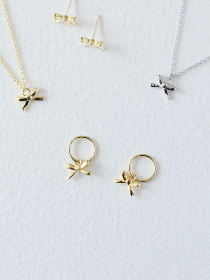 Gold and silver jewelry with bow designs on a white background