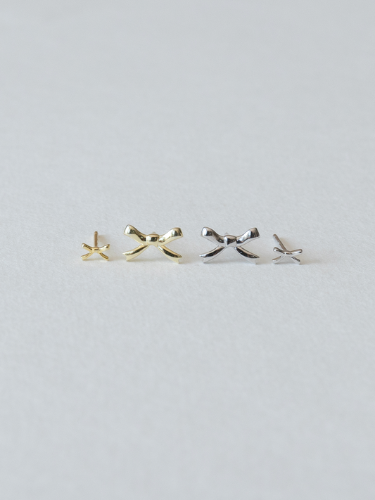 Pair of gold and silver bow-shaped earrings on a light gray background