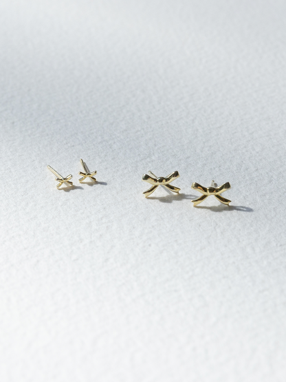 Gold bow-shaped earrings on a white background