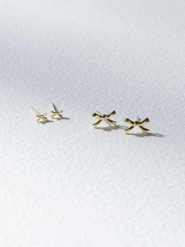 Gold bow-shaped earrings on a white background