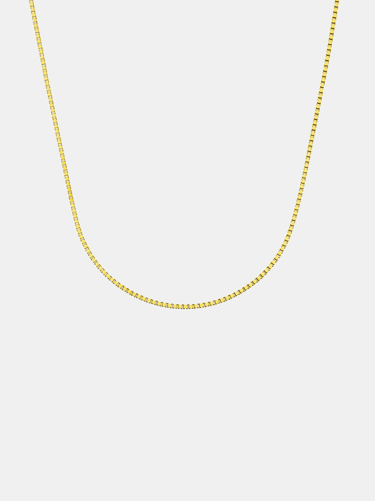 Gold chain necklace on a light gray background