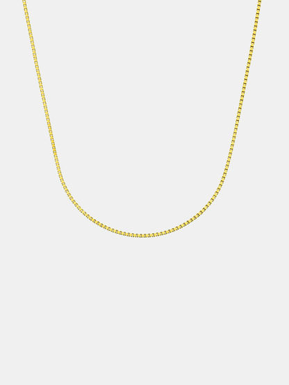 Gold chain necklace on a light gray background