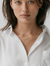 Gold box chain necklace stacked with the bar necklace on a model wearing a white shirt
