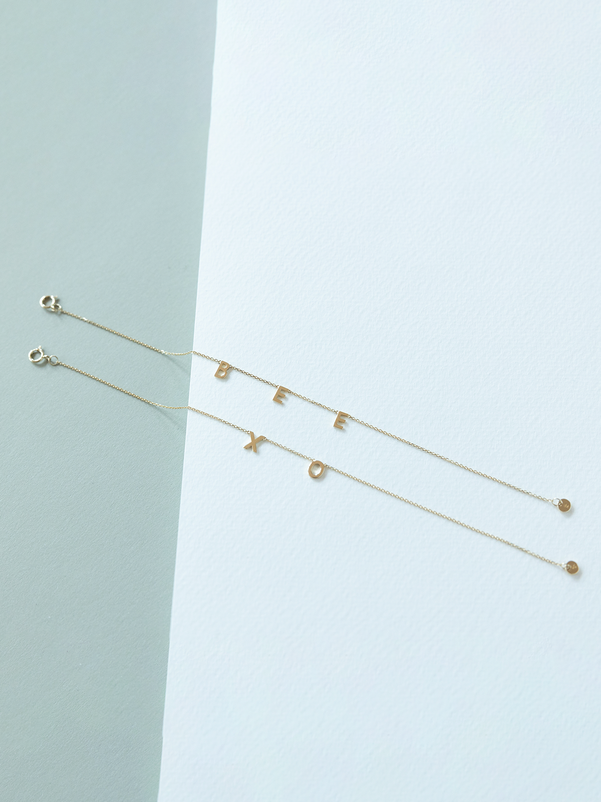 Solid gold choose your letters bracelets on a light blue background