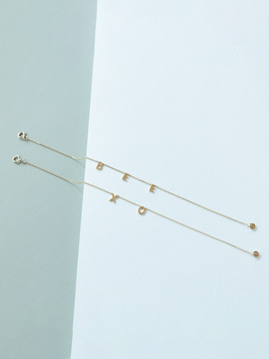 Solid gold choose your letters bracelets on a light blue background