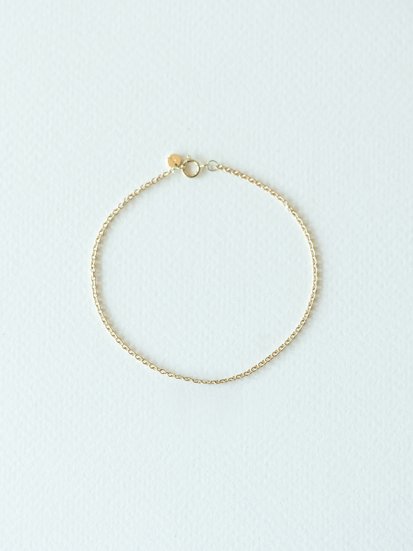 Gold bracelet on a light blue background